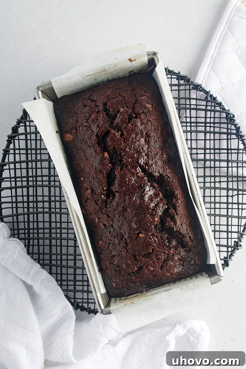 An overhead view of a freshly baked Chocolate Zucchini Bread loaf cooling on a wire rack.