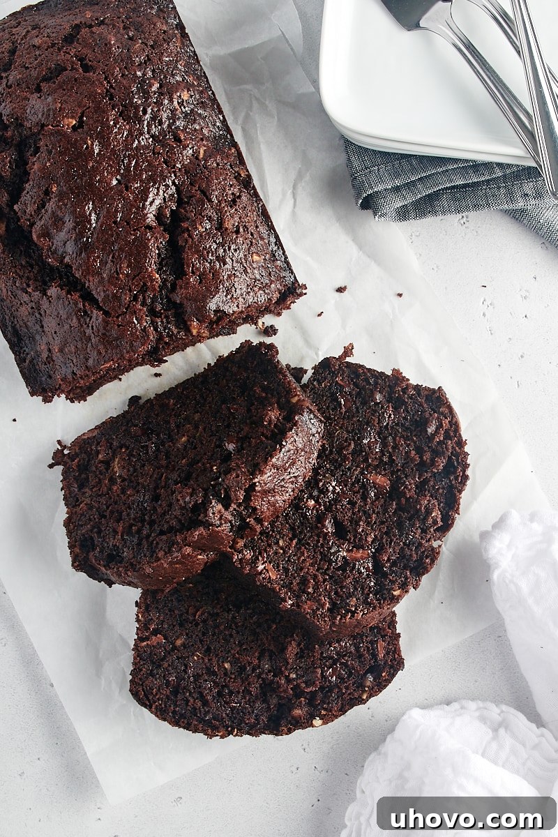 An overhead view of a partially sliced loaf of Chocolate Zucchini Bread, resting on a wire rack.
