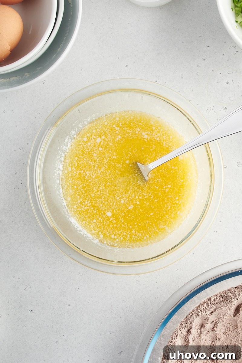 An overhead view of the mixed wet ingredients for Chocolate Zucchini Bread, including melted butter, eggs, milk, and vanilla.