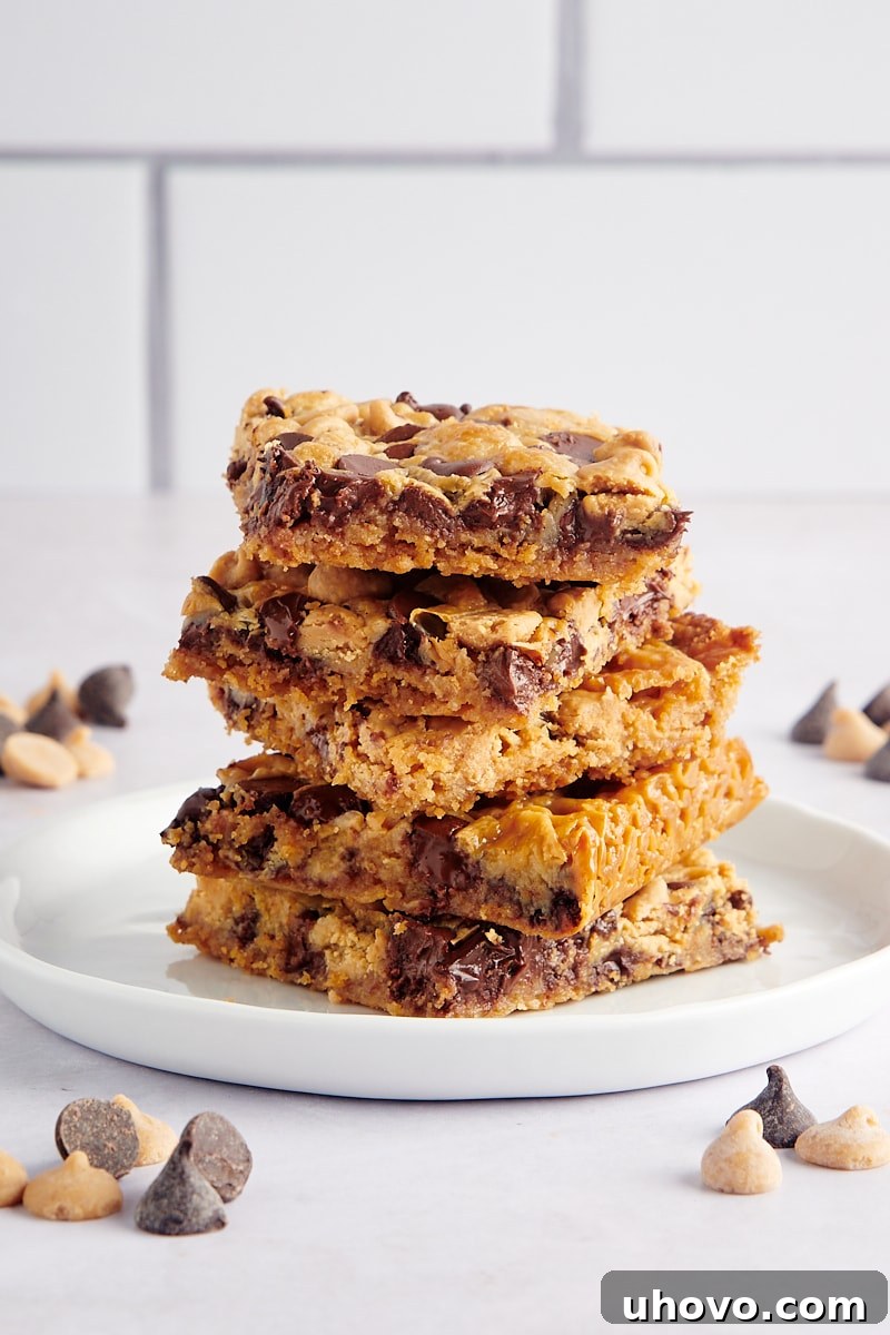 A beautiful stack of Double Delicious Cookie Bars on a white plate, highlighting their tempting golden-brown tops and generous chocolate and peanut butter chip layers.