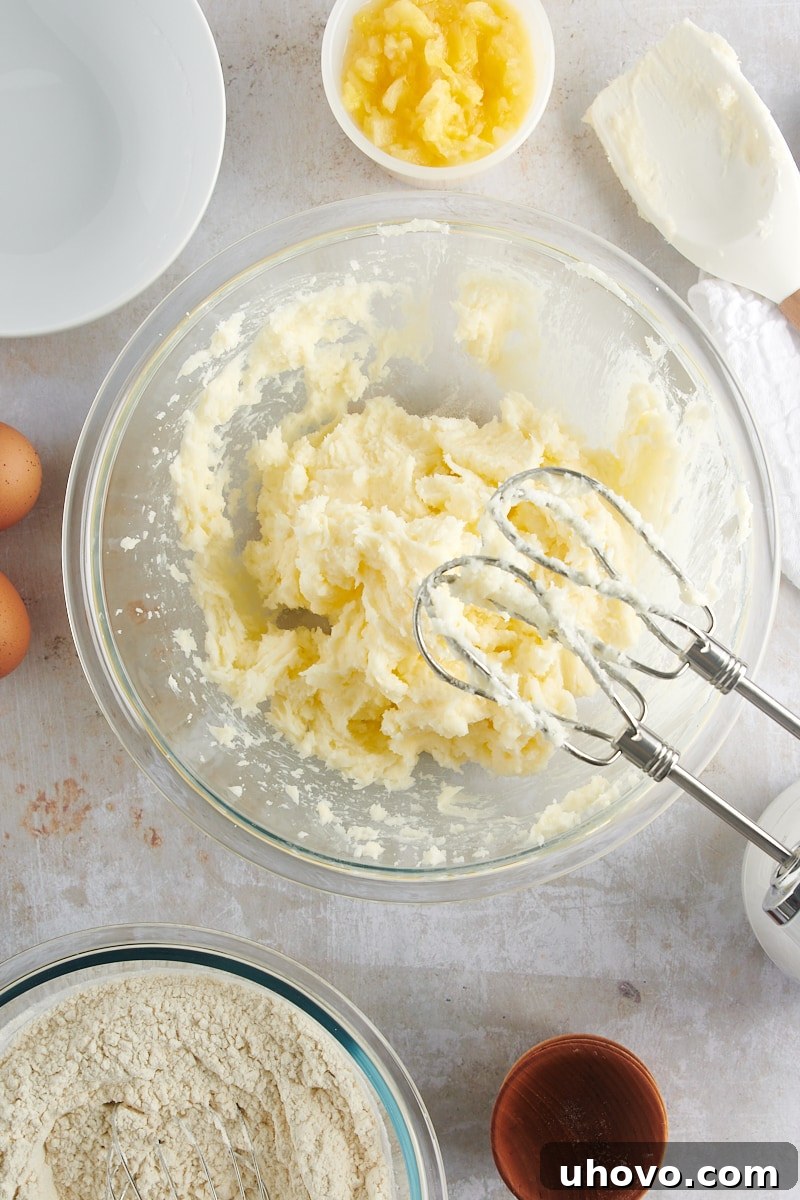 Overhead view of softened butter, cream cheese, and granulated sugar expertly mixed and creamed in a glass mixing bowl