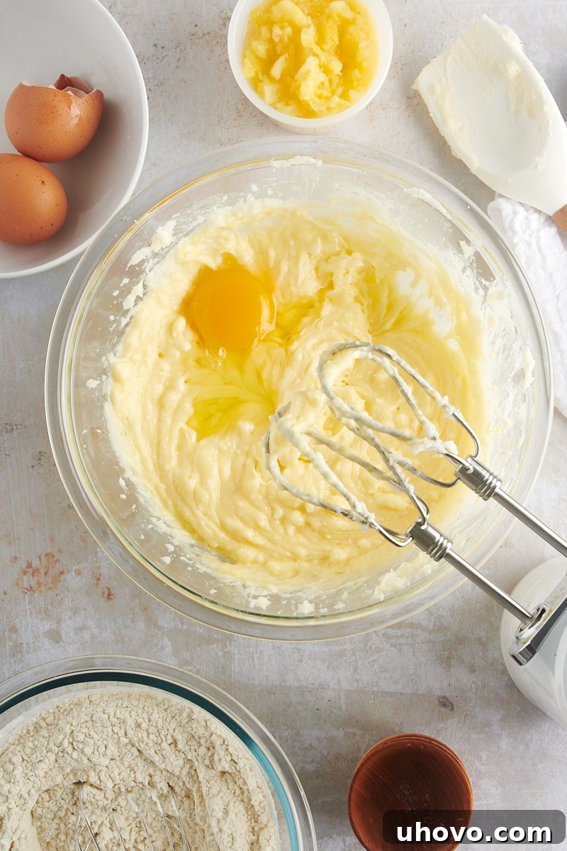Overhead view of an egg being cracked into the creamy cookie dough mixture, ready for incorporation