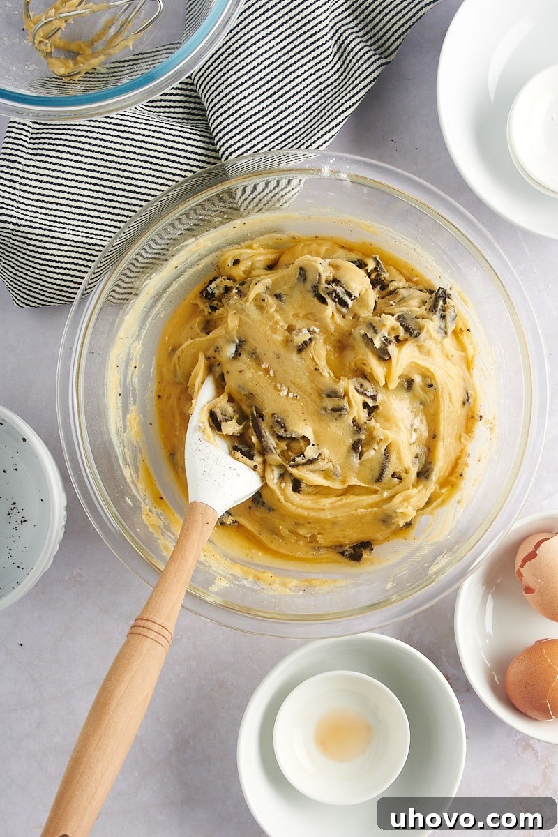 Overhead view of the mixed Cookies and Cream Blondies batter still in the glass mixing bowl, before transferring to the pan.