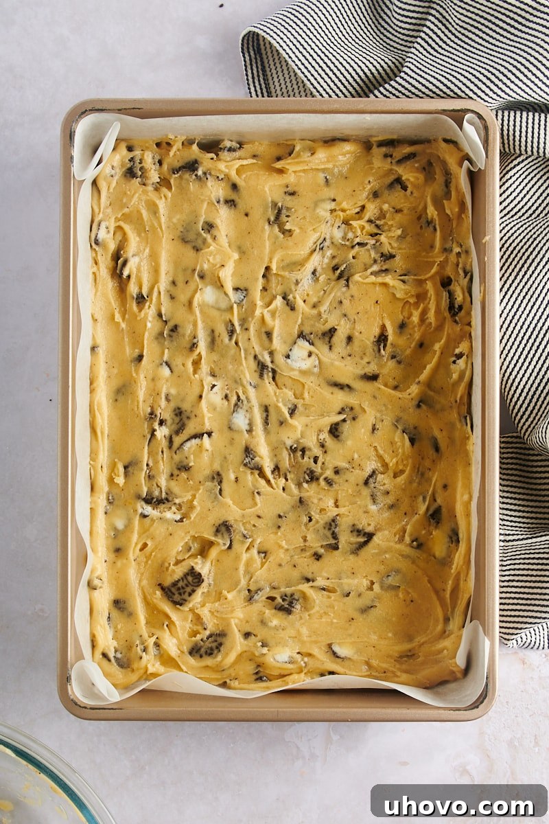 Overhead view of the Cookies and Cream Blondies batter evenly spread in a 9" x 13" baking pan, ready for the oven.