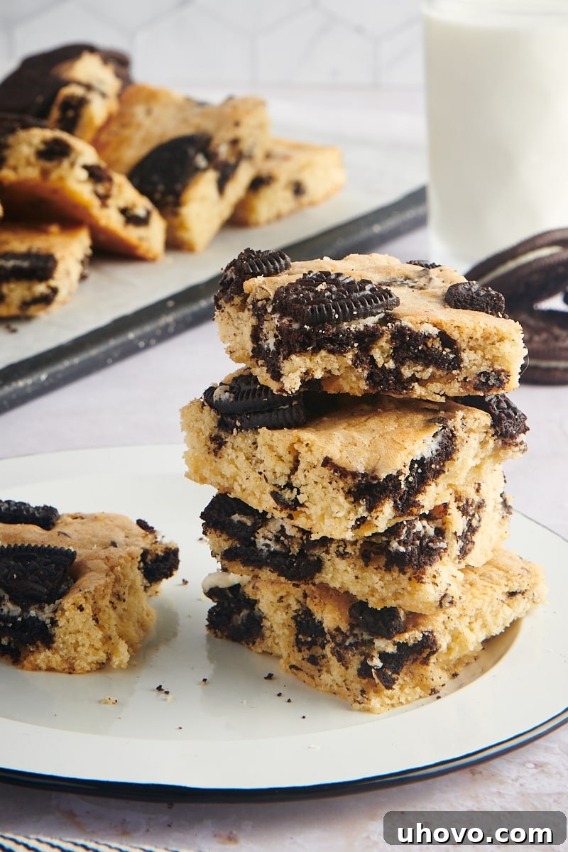 A perfectly stacked set of Cookies and Cream Blondies on a elegant black-rimmed white plate, ready to be served.
