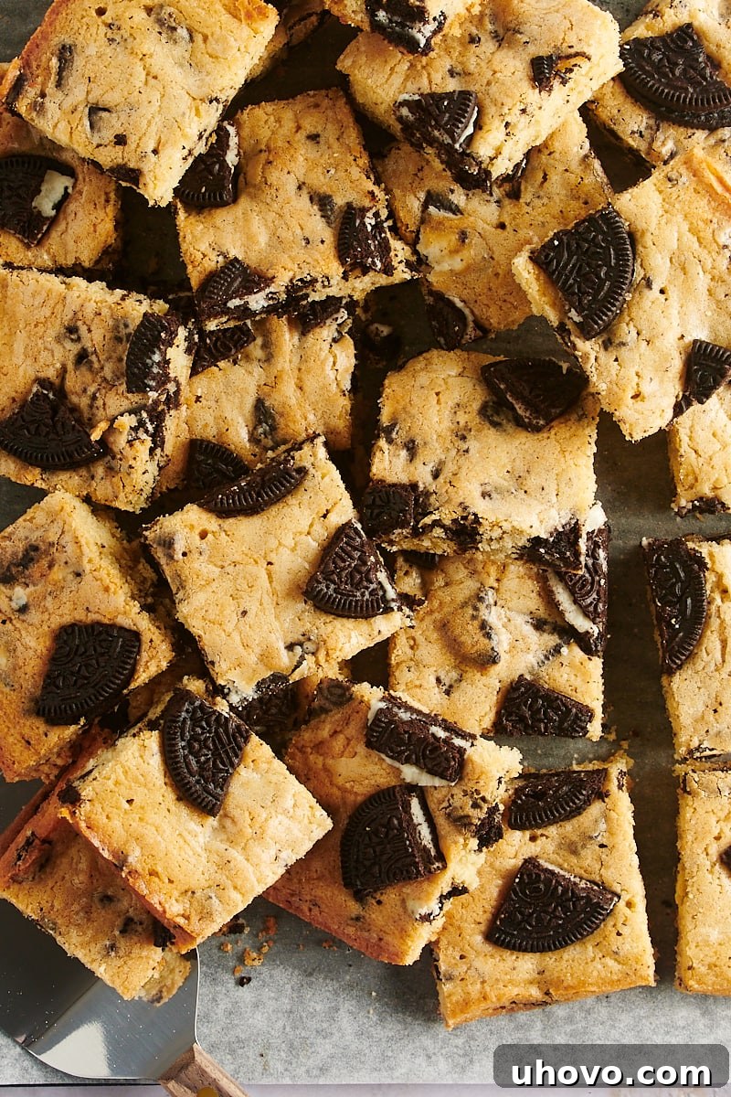 Overhead view of sliced Cookies and Cream Blondies, artfully piled on parchment paper.