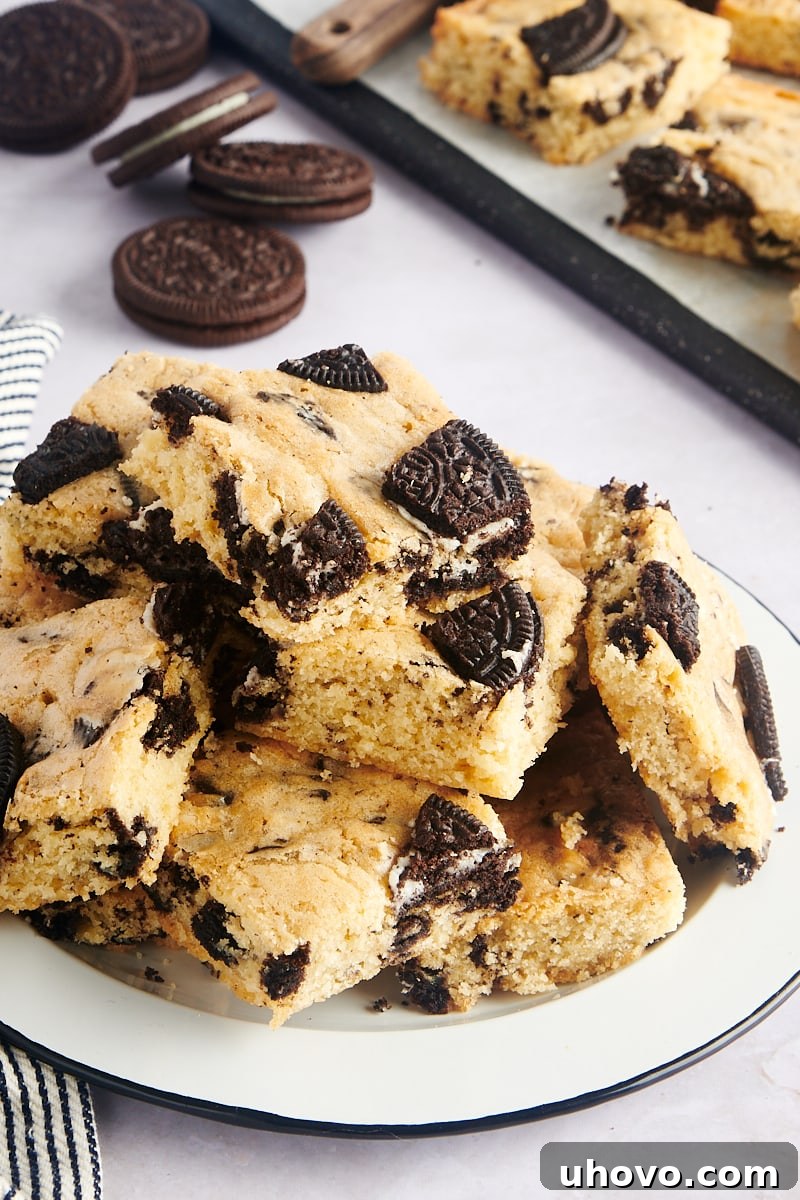 A beautiful pile of freshly baked Cookies and Cream Blondies arranged on a black-rimmed white plate.
