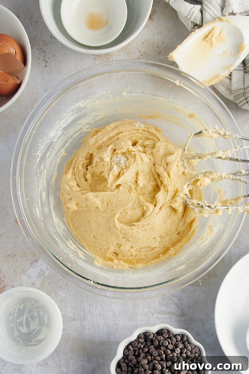 An overhead view displays the finished cake batter for Mini Chocolate Chip Bundt Cakes, smooth and well-mixed in a glass bowl, ready for the final touches.
