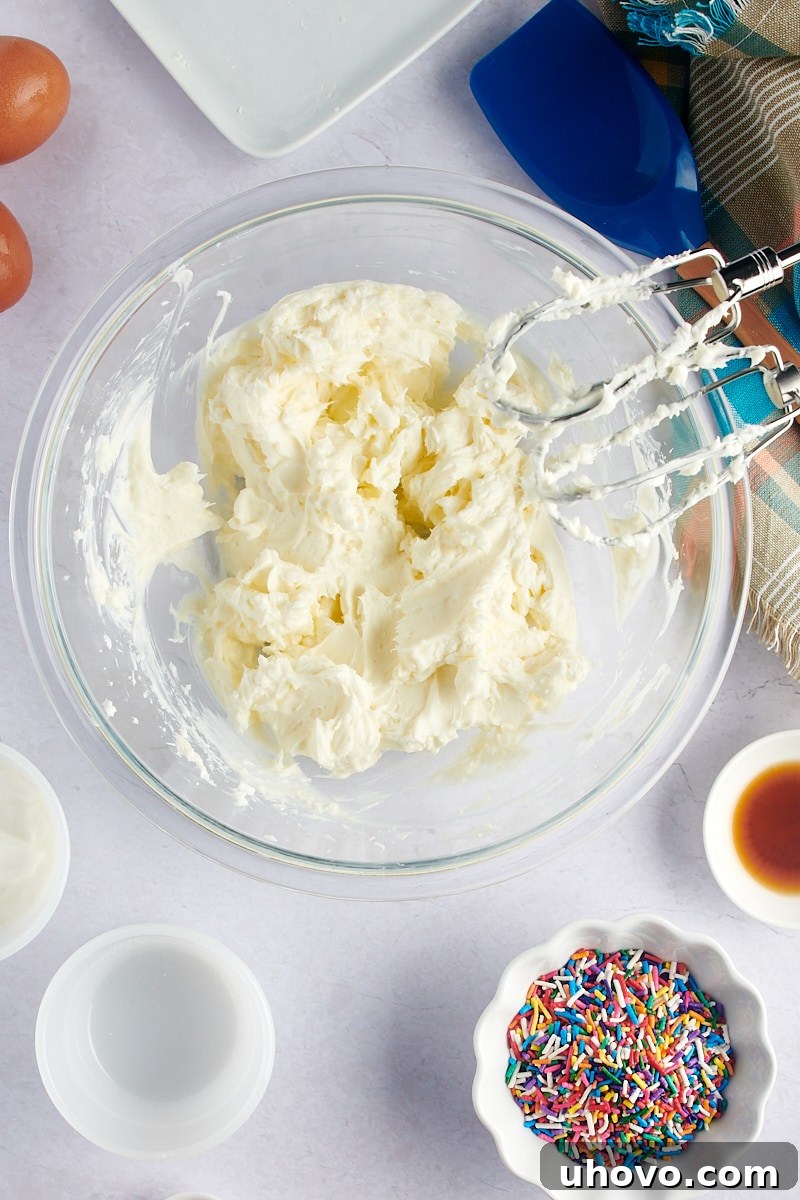 An overhead view of the smooth, creamy mixture of cream cheese and sugar after being thoroughly beaten in a mixing bowl.