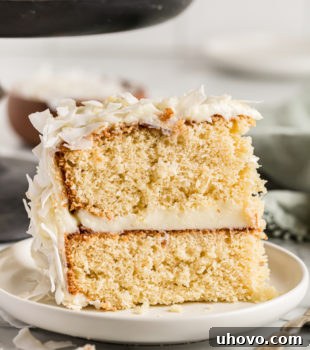 Slice of coconut cake standing upright on plate
