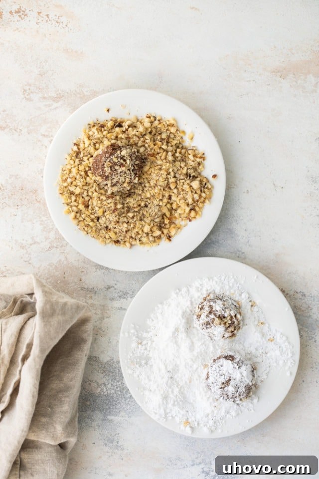 Hazelnut crinkle cookies dough being rolled in chopped hazelnuts and confectioners' sugar.