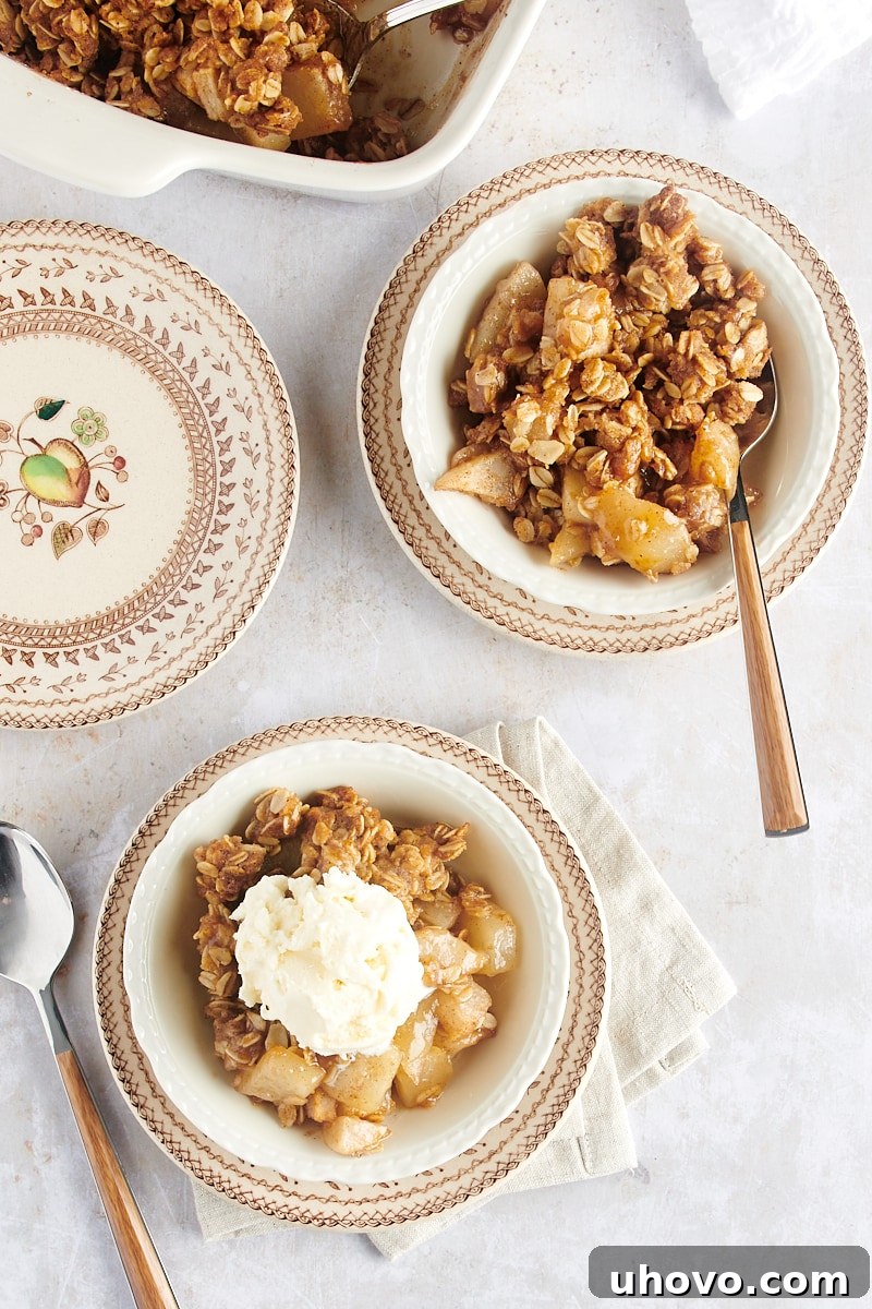 An overhead shot showcasing two individual servings of Brown Butter Pear Crisp, nestled in elegant white bowls, inviting a delightful dessert experience.