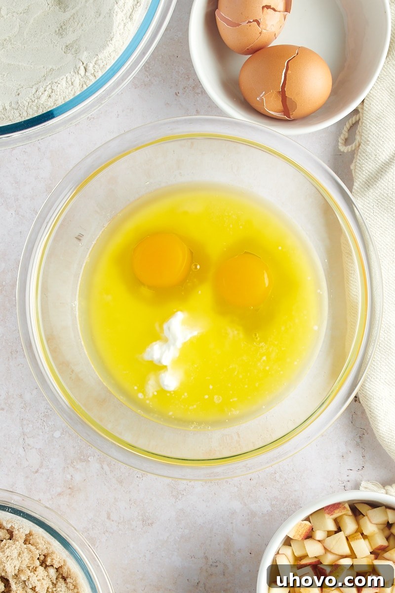 overhead view of butter, sour cream, milk, and eggs in a glass mixing bowl
