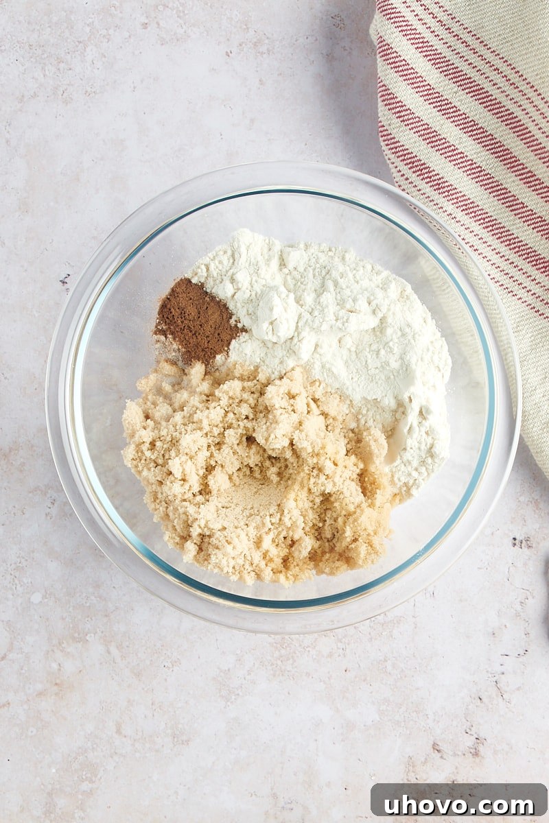 overhead view of flour, brown sugar, cinnamon, and salt in a glass mixing bowl