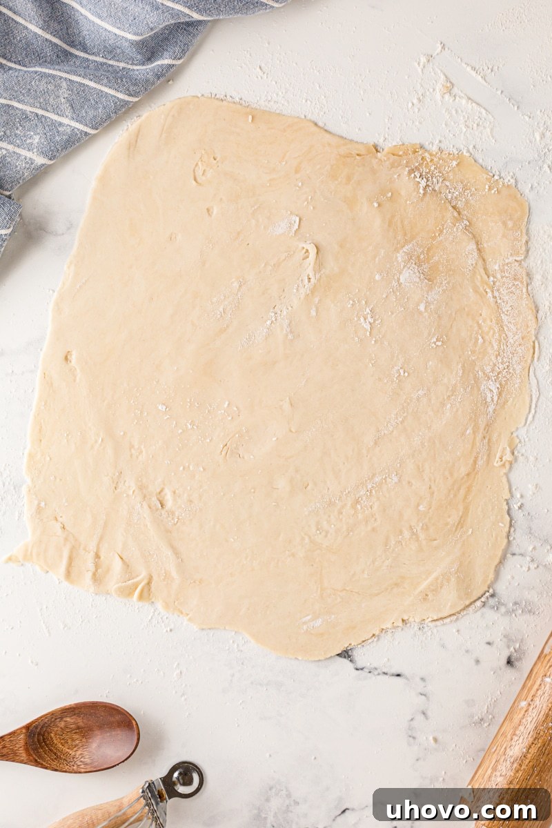 Overhead view of a perfectly rolled out pie crust, forming a smooth, even circle on a lightly floured surface, ready for transfer to a pie pan.
