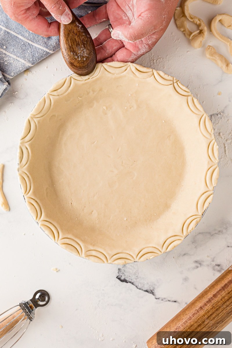 Close-up of a pie crust edge decorated with elegant scalloped indentations made using the back of a spoon, offering a simple yet beautiful design.