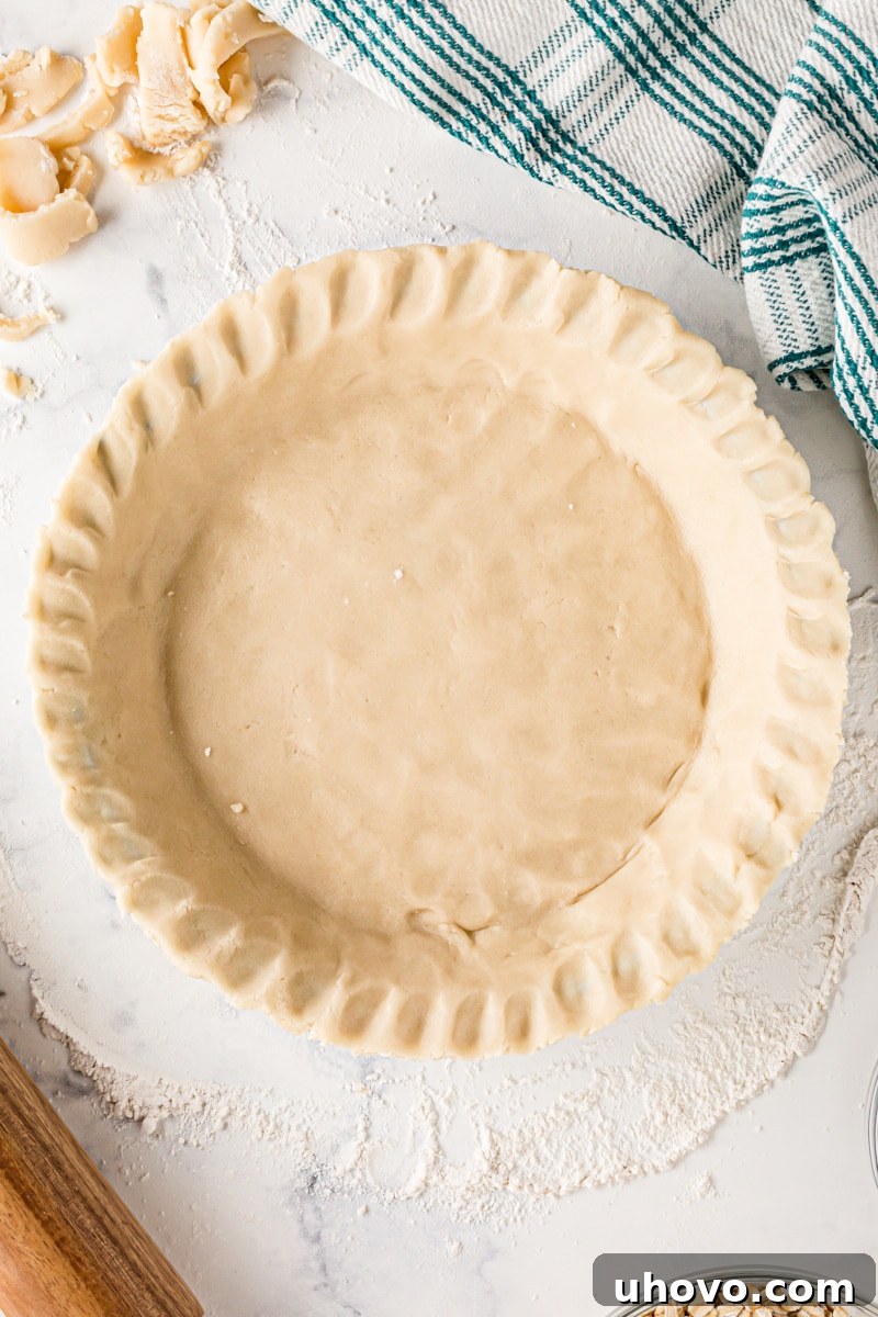Close-up of a beautifully fluted pie crust edge, showcasing a classic and elegant decorative finish achieved by pinching the dough.