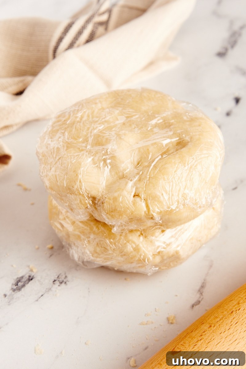 Two plastic-wrapped discs of homemade pie dough, showcasing the preparation for a double-crust pie or two single-crust pies. This image emphasizes the readiness and ease of storing homemade dough.