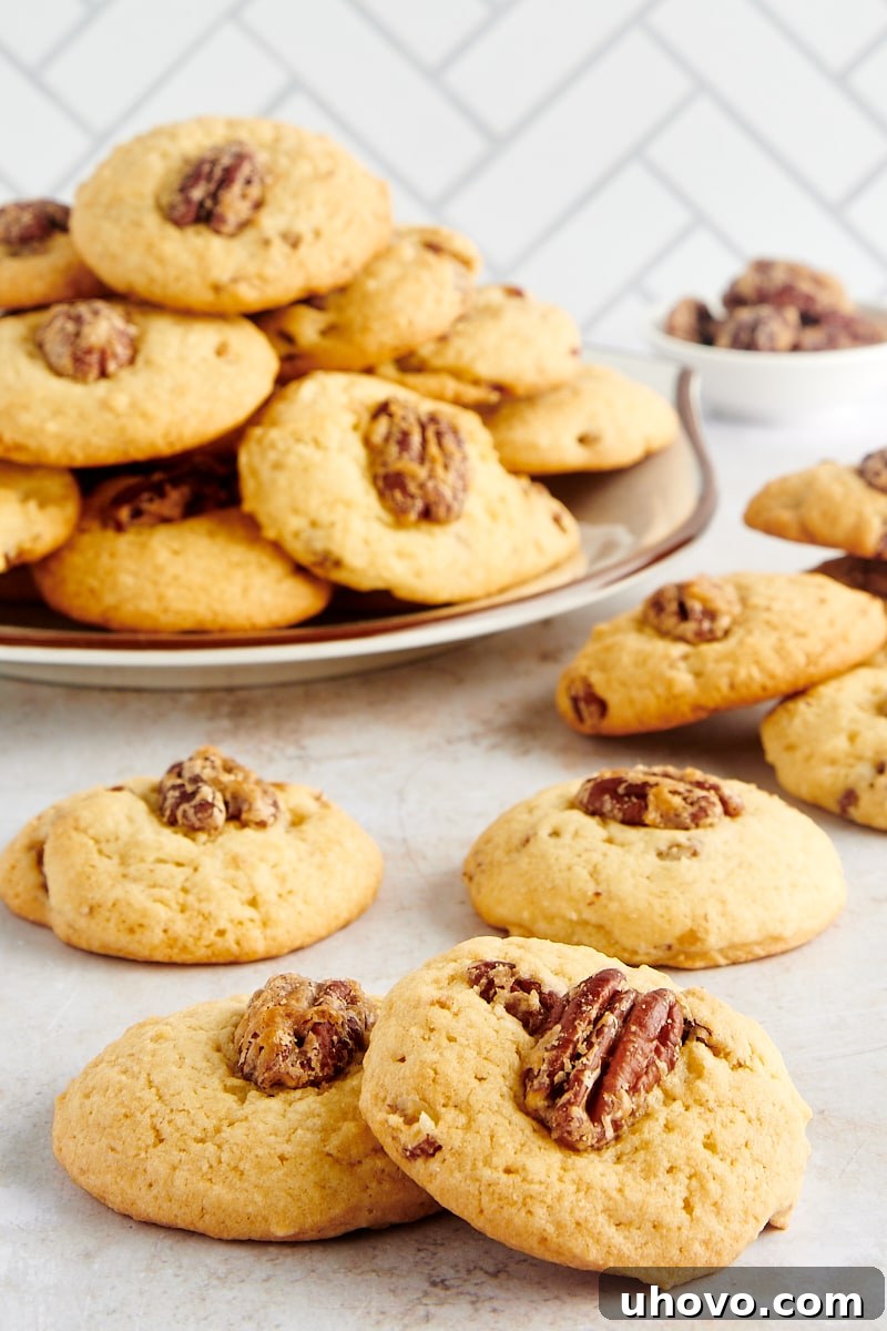 Delicious Maple Pecan Cookies scattered on a countertop with more cookies on a plate in the background, ready to be enjoyed.