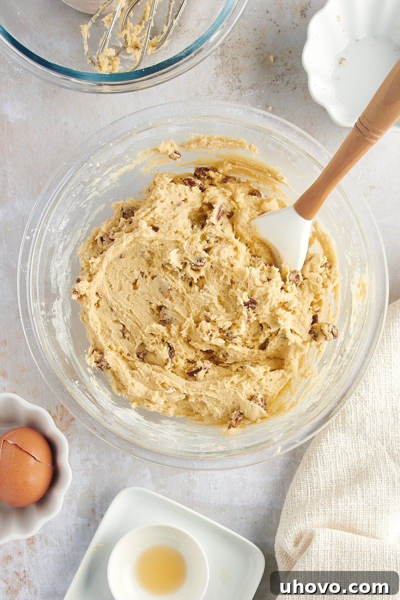 Overhead view of the perfectly mixed Maple Pecan Cookie dough with pecans evenly distributed in a glass mixing bowl.