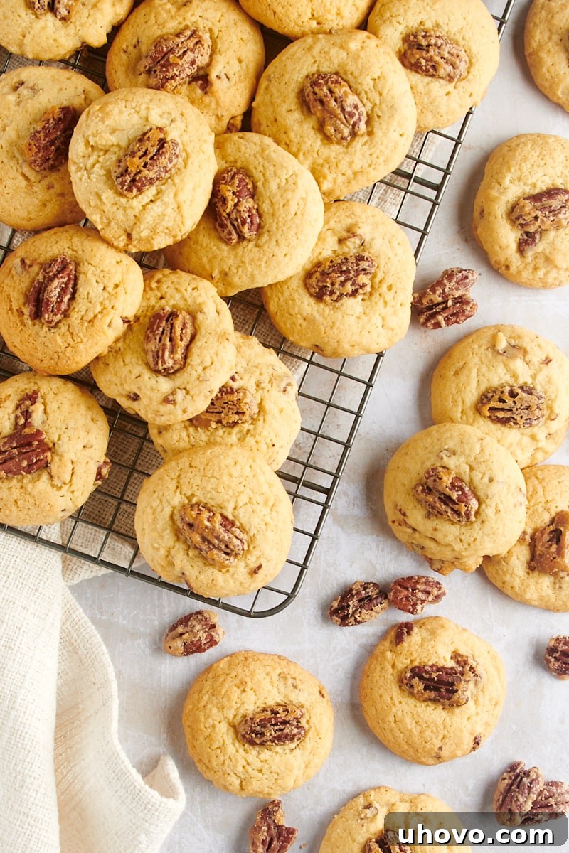Overhead view of warm Maple Pecan Cookies cooling on a wire rack and scattered on a countertop, ready to be enjoyed.