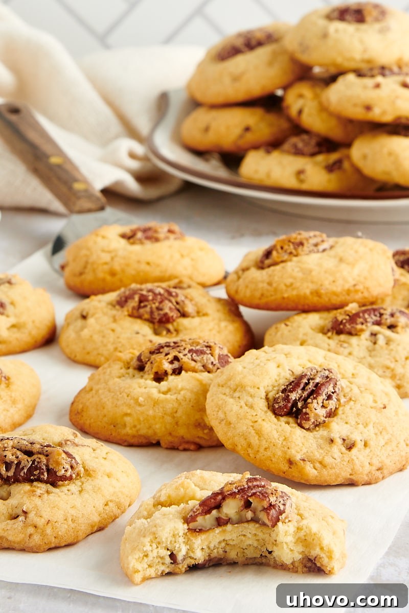 Maple Pecan Cookies elegantly displayed on parchment paper with a plate of more cookies in the background, highlighting their rich texture.