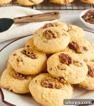 Maple Pecan Cookies stacked neatly on a white and brown-speckled plate, showcasing their inviting appearance.