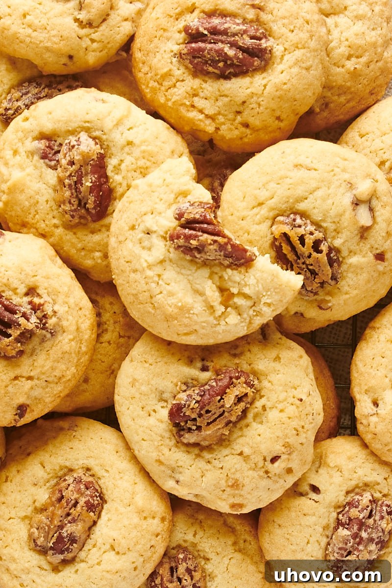 Overhead view of a crowded pile of freshly baked Maple Pecan Cookies, showcasing their golden-brown edges and inviting texture.