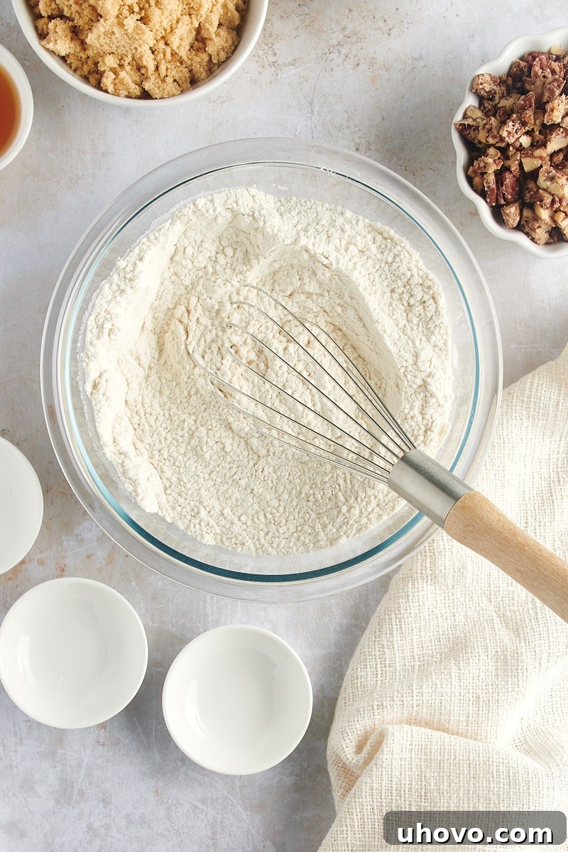 Overhead view of the mixed dry ingredients for Maple Pecan Cookies in a glass mixing bowl, perfectly combined.