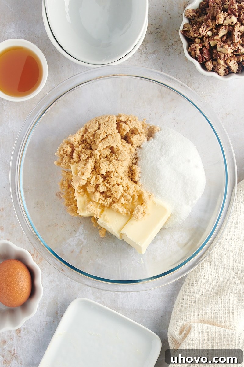 Overhead view of softened butter, brown sugar, and granulated sugar in a glass mixing bowl, ready for creaming.