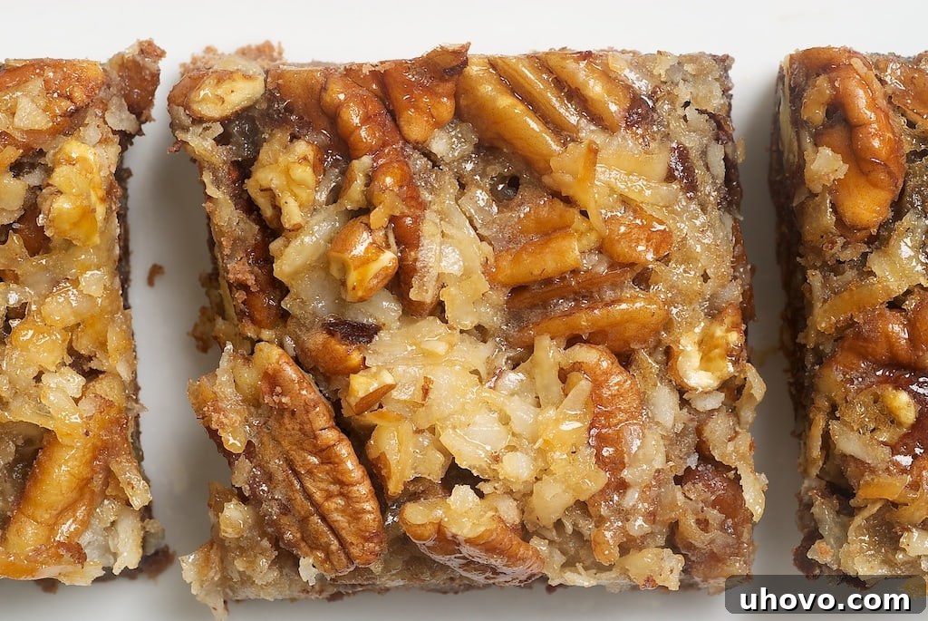 Close-up of German Chocolate Pecan Pie Bars on a white plate, highlighting the texture of the filling and crust.