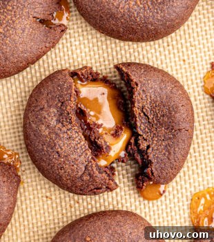 Overhead view of chocolate caramel cookie broken in half to show gooey middle