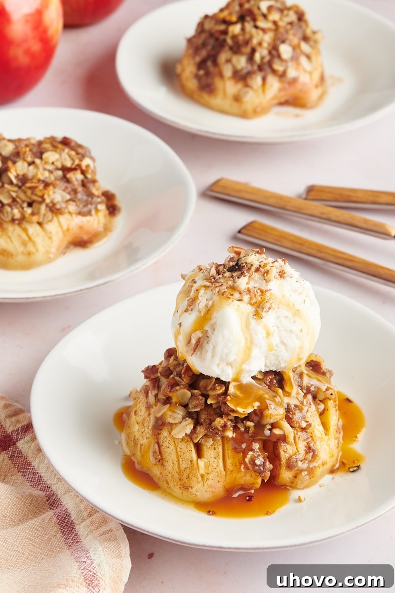Three individual servings of baked hasselback apples, presented on white plates with a minimalistic garnish