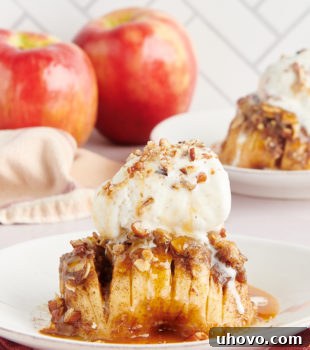 A baked hasselback apple topped with a scoop of vanilla ice cream, drizzled with caramel sauce, and sprinkled with chopped nuts