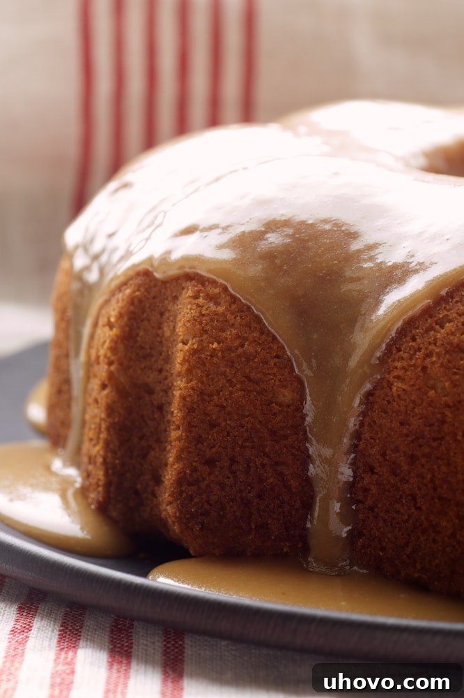 Close-up view of a slice of Caramel Bundt Cake on a dark gray cake plate, showing its moist texture and rich caramel drizzle