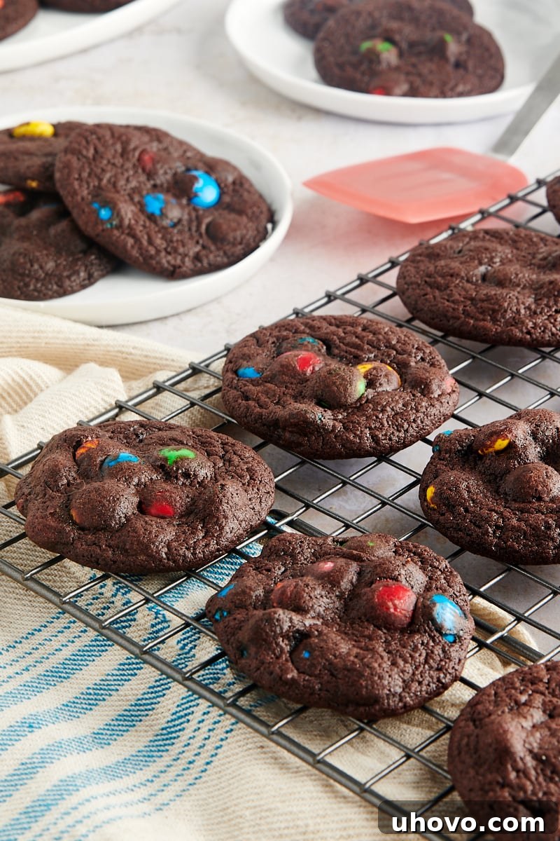 Delicious Chocolate M&M Cookies arranged neatly on a silver wire cooling rack, allowing them to cool completely.