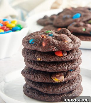 Stack of Chocolate M&M Cookies on a white plate, showcasing their inviting appearance.