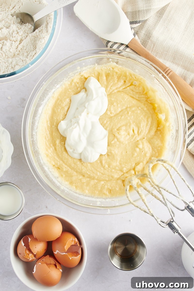 overhead view of sour cream being added to Marble Bundt Cake batter