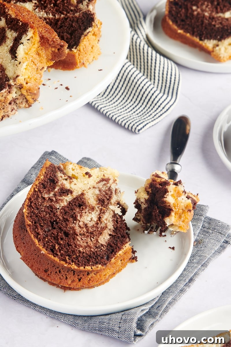 slice of Marble Bundt Cake on a white plate with a bite taken, showing the tender crumb