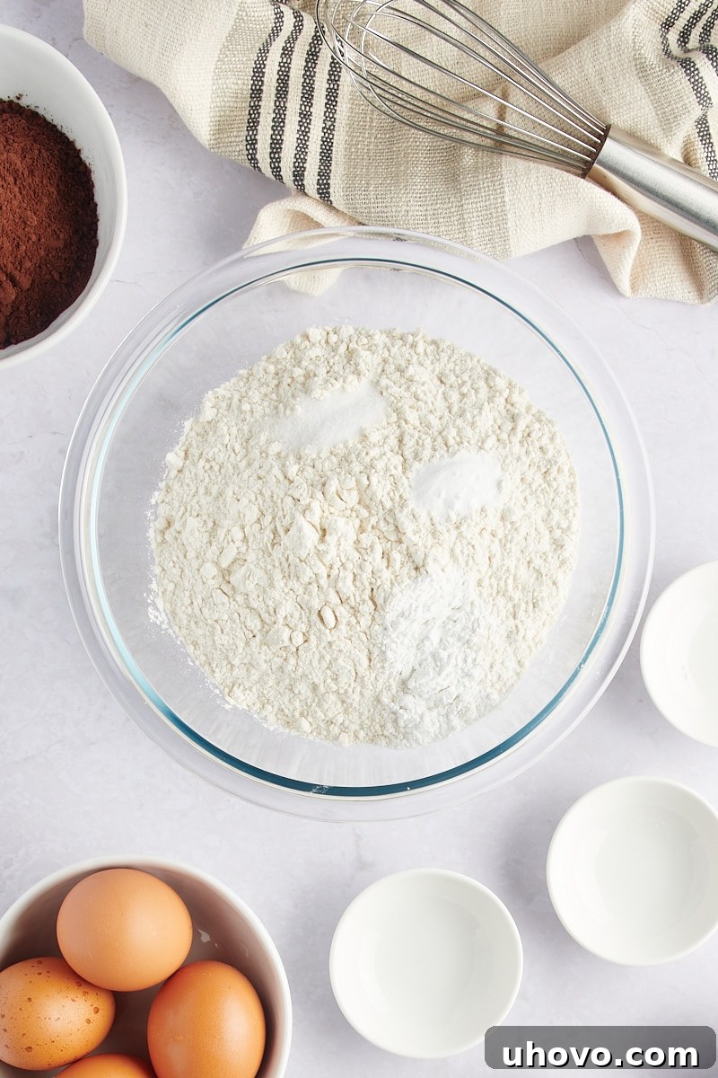 overhead view of flour, baking powder, baking soda, and salt in a glass mixing bowl