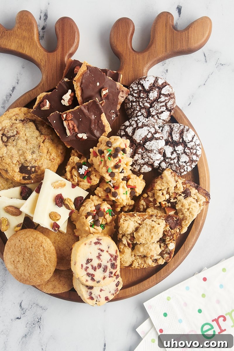 An overhead shot of various holiday cookies and candies beautifully arranged on a rustic wooden board, ready to be shared.