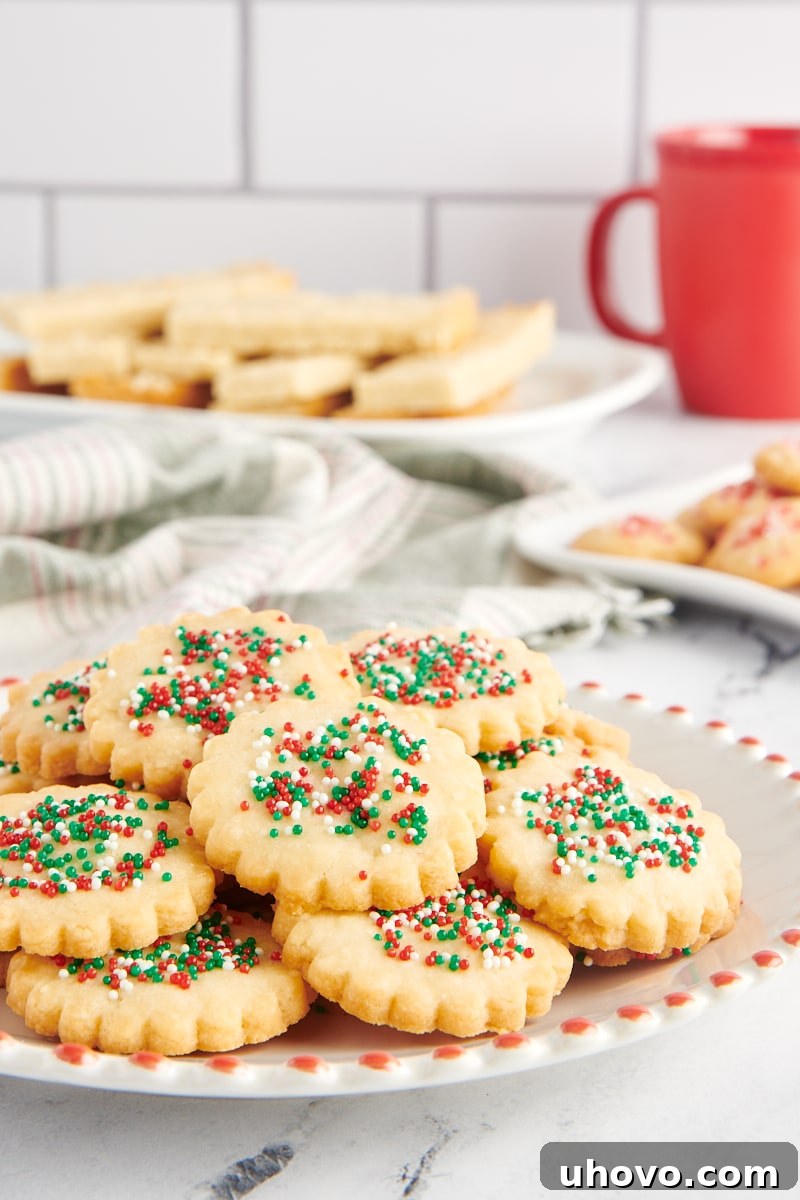 Shortbread cookies on a red-rimmed white plate with more cookies on plates in the background.