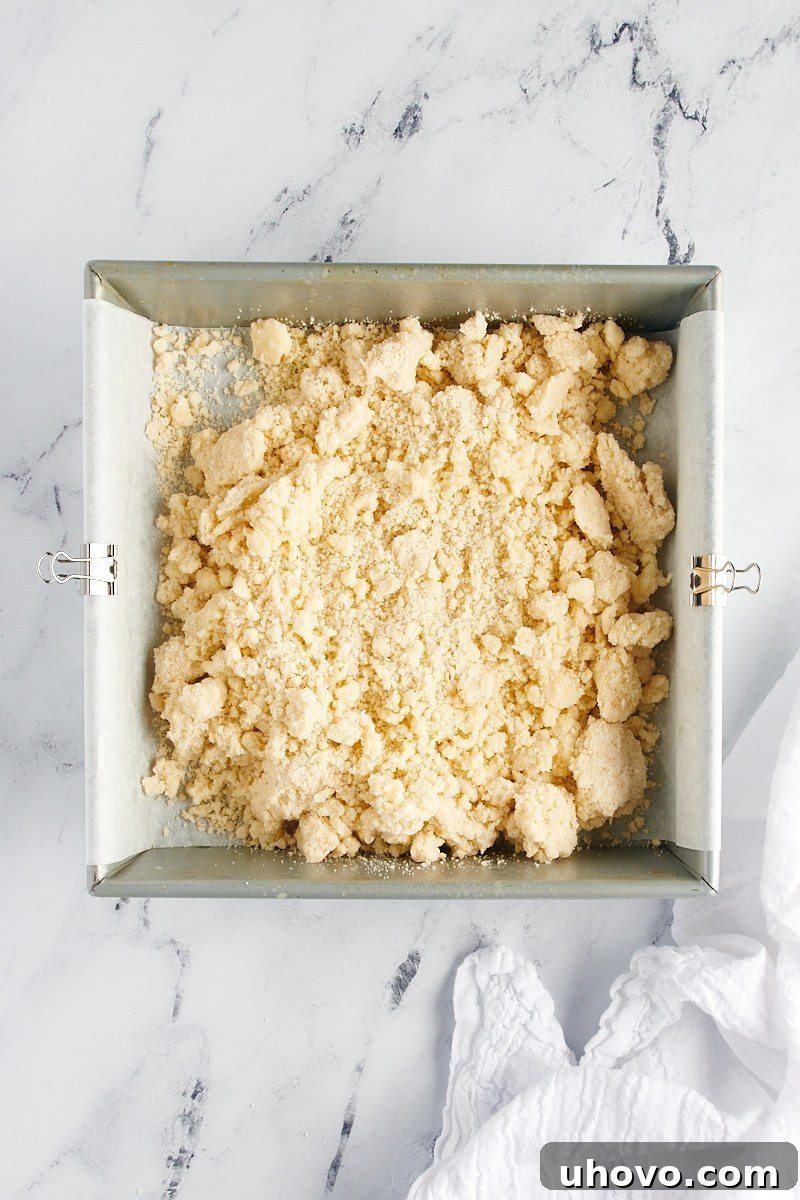Overhead view of shortbread cookie dough in a parchment-lined square baking pan.