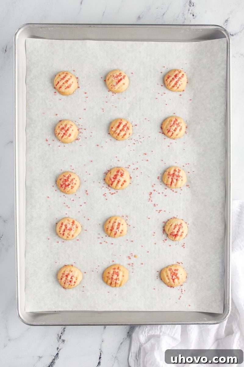 Overhead view of freshly baked drop shortbread cookies on a baking sheet.