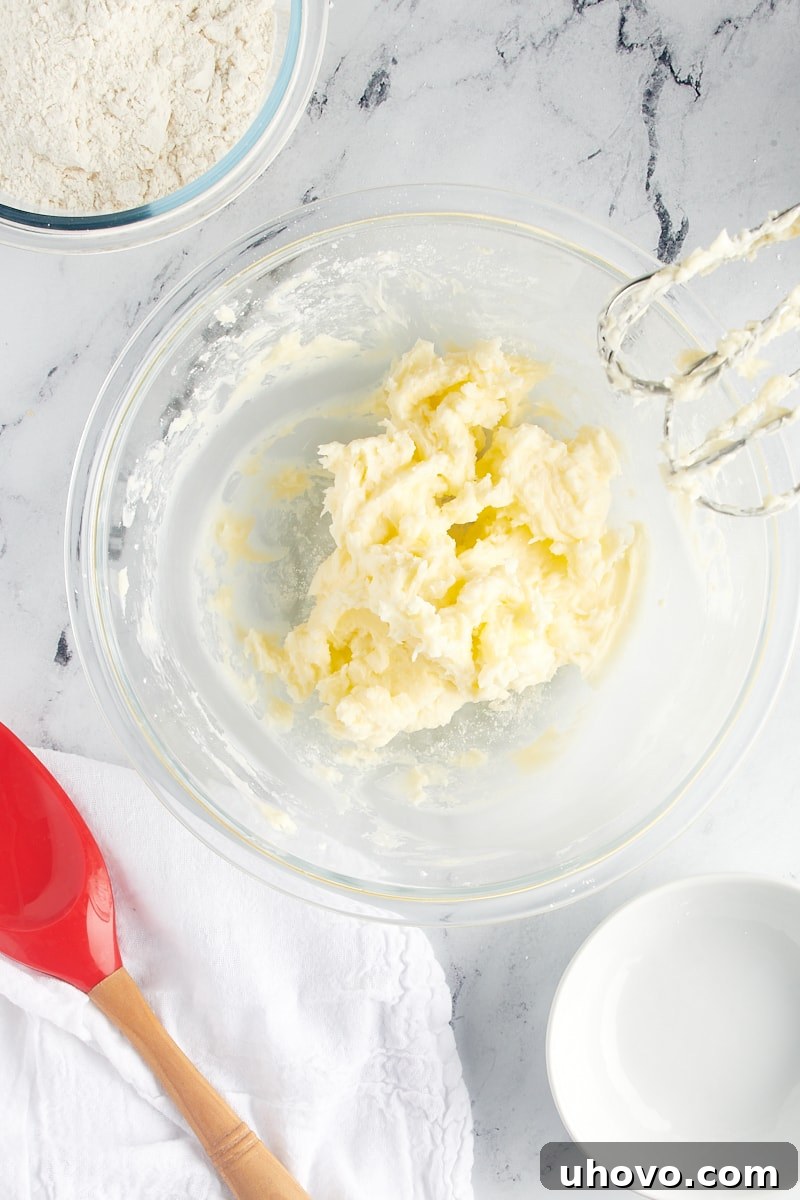 Overhead view of creamed butter and confectioners' sugar in a glass mixing bowl.