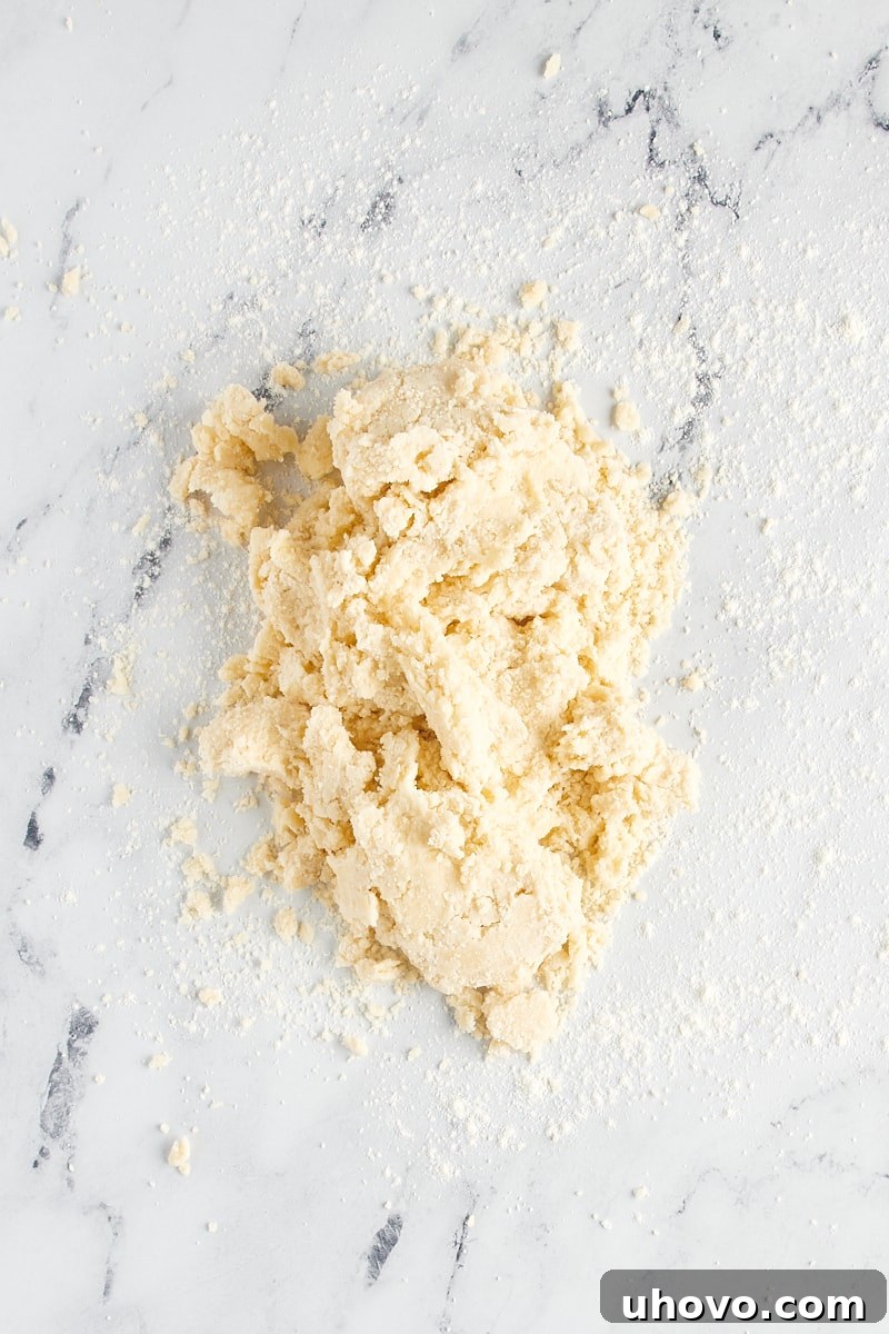 Overhead view of shortbread cookie dough on a lightly floured marble surface.