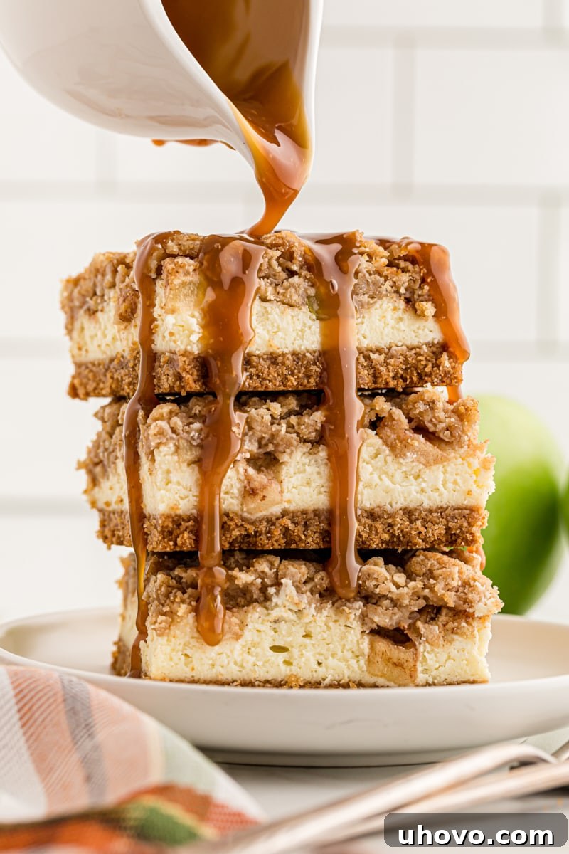 caramel sauce pouring over a stack of three Caramel Apple Cheesecake Bars