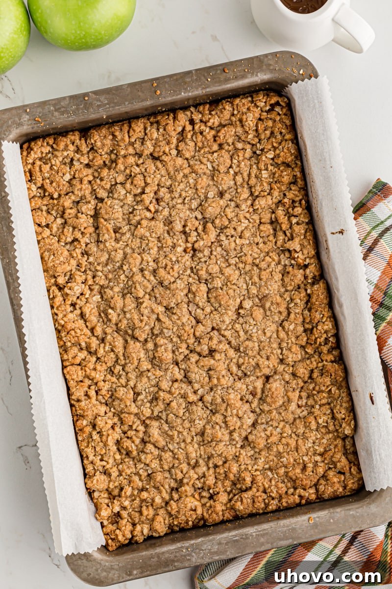 overhead view of freshly baked Caramel Apple Cheesecake Bars in a parchment- lined baking pan
