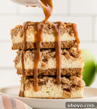 caramel sauce pouring over a stack of three Caramel Apple Cheesecake Bars