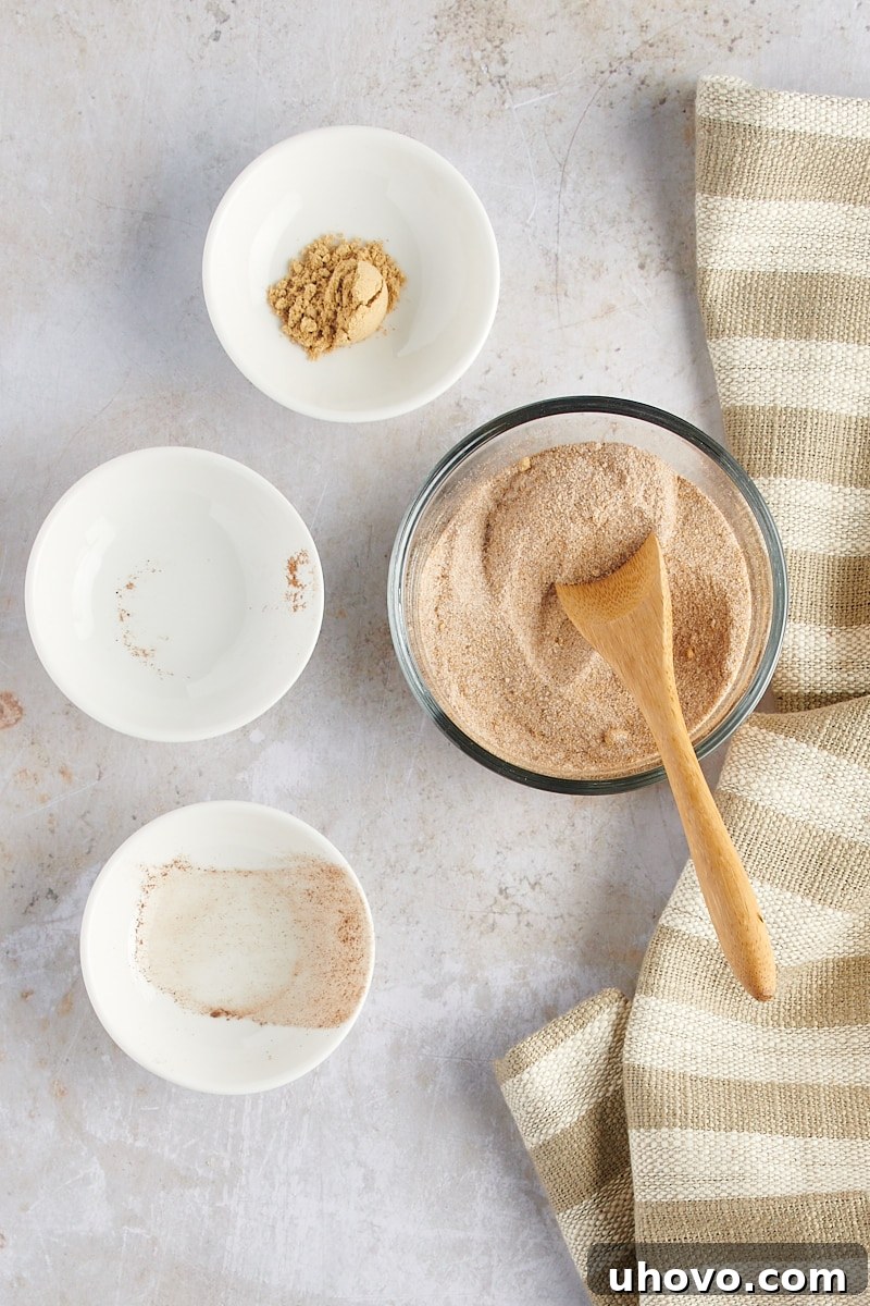 Overhead view of the mixed spiced sugar coating ingredients in a clear glass bowl, showcasing the uniform blend of sugar, ginger, cinnamon, and nutmeg.